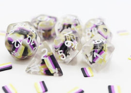 A colorful Nonbinary Flag RPG Dice Set by Foam Brain, featuring various polyhedral dice in a clear resin material. Each die is adorned with the nonbinary flag colors of yellow, white, purple, and black, with clear numbering for easy reading. The set includes multiple types of dice, perfect for tabletop role-playing games, surrounded by small flag-themed accents.