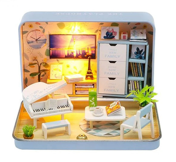 Happiness Theater DIY in Tin by Guangzhou Hongda Craft Co., Ltd. is a detailed DIY miniature model kit showcasing a cozy living room. The scene features a white piano, a modern coffee table with books, a quaint chair, indoor plants, and a decorative light illuminating the setup. The background includes wall art and functional furniture pieces, providing a charming atmosphere for creative crafting.