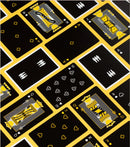 A vibrant card deck featuring a unique design with black background and yellow accents. The cards show various traditional suits and royal figures, perfect for game nights. Designed by Art of Play, this deck combines playfulness and artistry for an engaging gaming experience.