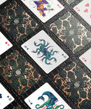 A detailed image of the Forbidden Forest Card Deck featuring beautifully illustrated playing cards. The cards showcase intricate designs with mythical creatures and vibrant colors set against a dark, textured background. Various card values are visible, enhancing the enchanting theme of the deck.