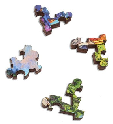 A close-up view of four intricately designed wooden jigsaw puzzle pieces from the 'Floating Town' puzzle by Roch Urbaniak, showcasing vibrant colors and unique shapes. The pieces feature a mix of watercolor-like patterns in blue, green, and orange tones, highlighting the artistic design of the puzzle.