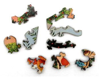 Close-up view of several uniquely shaped wooden jigsaw puzzle pieces from the 'Pride of Peacocks' puzzle by Marie Amalia. The pieces feature vibrant colors and intricate designs, showcasing sections of majestic peacocks and lush greenery, highlighting the craftsmanship of Artifact Wooden Puzzles.