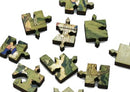 A collection of intricately shaped wooden jigsaw puzzle pieces featuring scenes of nature and serene figures. The pieces showcase detailed artwork, including lush greens and soft colors, suggesting a tranquil landscape. Each piece has unique designs and a smooth finish, ideal for puzzle enthusiasts and collectors.