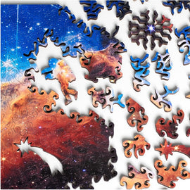 A colorful jigsaw puzzle featuring Cosmic Cliffs Infinite Galaxy design by Nervous System. The image shows vibrant space imagery with pieces in various shapes, including an astronaut and cosmic elements, waiting to be assembled.