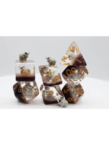 A colorful set of Elephant RPG dice displaying various shapes, featuring numbers in gold and small elephant figurines on top of some dice. The dice are arranged in stacks and have a translucent finish, showcasing intricate details.