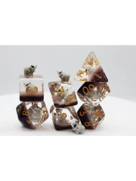 A colorful set of Elephant RPG dice displaying various shapes, featuring numbers in gold and small elephant figurines on top of some dice. The dice are arranged in stacks and have a translucent finish, showcasing intricate details.