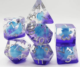A vibrant Blue Stegosaurus RPG Dice Set featuring seven polyhedral dice in a blend of blue and purple colors with silver numbers. The set includes a d20, d12, d10, d8, d6, d4, and a d3, showcasing a unique dinosaur design within the translucent resin.