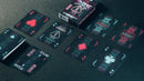 A vibrant set of Bicycle Cyberpunk Cybercity playing cards spread out on a dark surface. The cards feature futuristic designs with neon colors, including Ace cards and Jokers, all packaged in an eye-catching box that showcases the Cybercity theme.