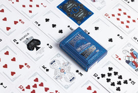 A deck of Bicycle Back to the Future playing cards displayed on a table. The blue card box features iconic imagery from the popular film franchise. Surrounding the box are various playing cards showing vibrant designs, including hearts, clubs, and special illustrations that celebrate the time-traveling theme of the series. This collectible card deck combines nostalgia with classic card game fun.