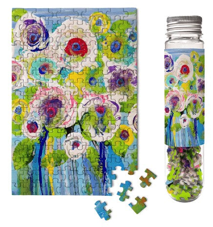 A colorful jigsaw puzzle titled 'Bouquet of Beauty' by Micro Puzzle. The puzzle features a vibrant floral design with various shades of green, pink, and blue. Next to the puzzle, a clear plastic tube holds the small puzzle pieces, showcasing the same floral design on the outside.