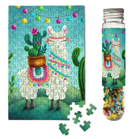A vibrant jigsaw puzzle featuring a festive llama adorned with colorful decorations and surrounded by cacti. The puzzle is housed in a clear, cylindrical container with a matching llama design. Several loose puzzle pieces are positioned in front of the puzzle, emphasizing its playful and colorful theme.