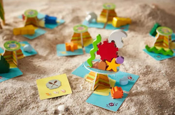 Flotsam Float game by Haba featuring colorful stacking pieces and vibrant underwater-themed cards set against a sandy backdrop. Ideal for group play and enhancing fine motor skills.