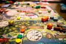 Close-up view of the Eternal Palace board game by Alley Cat Games. The vibrant game board features colorful tokens, dice, and various resource markers spread across different terrains. Players engage with elements like the Forest of Abundance and Spring Pavilion, highlighting its strategic gameplay.