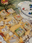 The Palaces of Carrara board game by GAME BREWER LLC showcasing an intricate game board with various building tiles and colored tokens. The board features the landscape of Carrara, Italy, emphasizing strategy and resource management.