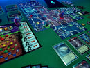 A vibrant tabletop game setup for Clank!: Catacombs. The game features a colorful board with various paths and tokens. Miniature characters in action, card decks, and a scoring board are neatly arranged, showcasing the strategic elements of the game.