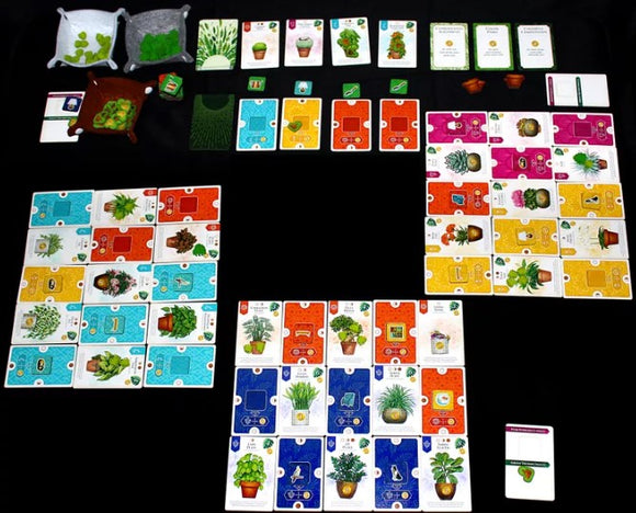 The game 'Verdant' by Alderac Entertainment Group, featuring colorful cards and game pieces laid out on a black surface. The game includes various plant-themed cards, pots, and tokens, promoting strategic gameplay focused on gardening and plant collection.
