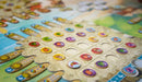 Close-up of the board game 'Fyfe' by Burnt Island Games, featuring colorful tokens and a vibrant game board with a beach and tropical theme. The board displays various icons and numbers, inviting players to engage in dynamic gameplay.