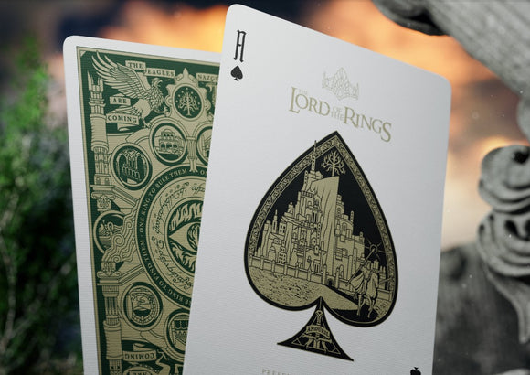 A stunning Lord of the Rings card deck by Theory 11, featuring the Ace of Spades with intricate gold detailing, depicting a castle. The reverse side showcases an elaborate green design with iconic symbols from Middle-earth, including the eagle and the Eye of Sauron, emphasizing the epic fantasy theme.