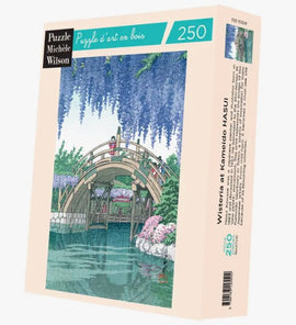 The Wisteria In Kameido jigsaw puzzle by Wilson Jeux features a serene scene with a wooden bridge over a calm waterway, surrounded by lush greenery and vibrant wisteria flowers. This beautifully illustrated puzzle has 250 pieces, showcasing intricate details and bright colors, ideal for puzzle enthusiasts and nature lovers.
