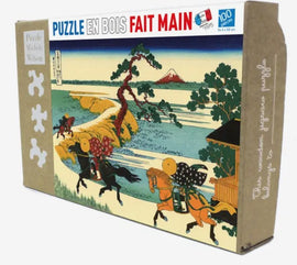 Fields of Sekiya jigsaw puzzle box by Wilson Jeux, featuring a vibrant artwork of a serene landscape with horses and a mountain backdrop. The box showcases 100 wooden pieces, perfect for puzzle enthusiasts.