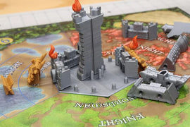 Castle Panic: 2nd Edition game components displayed. Features a central tower with flames, surrounded by various castle pieces and knights on a colorful game board. Ideal for strategy lovers.