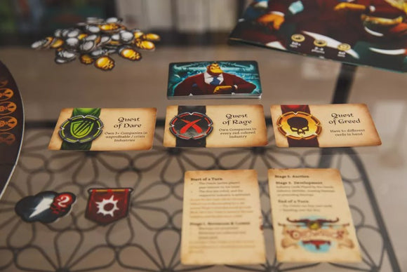 A close-up view of the board game Orconomics by ARES GAMES, featuring various character cards including "Quest of Dare," "Quest of Rage," and "Quest of Greed" alongside game components like tokens and turn order instructions.