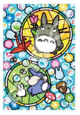 A colorful jigsaw puzzle featuring Totoro and other characters from the beloved anime. The design includes vibrant circular motifs with flowers, mushrooms, and glassy marbles, all set against a bright blue background, ideal for fans of Studio Ghibli and puzzle enthusiasts.