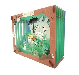 A whimsical Paper Theater DIY kit featuring Totoro and a child in a lush green field. The intricate layered design showcases vibrant colors and detailed cutouts, creating a charming 3D tableau.