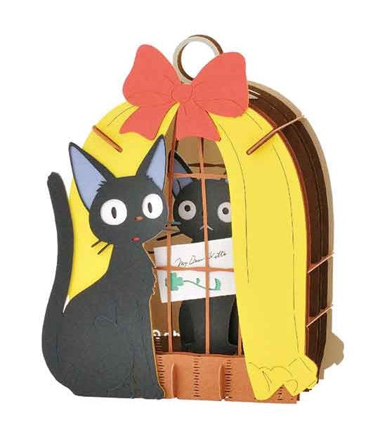 The Paper Theater Jiji in Cage by Ensky features a playful design of a black cat named Jiji standing beside a colorful cage adorned with a bright red bow and yellow curtains. The playful scene captures a whimsical and charming aesthetic, perfect for DIY enthusiasts.