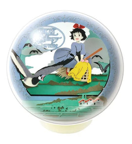 A beautifully crafted Paper Theater Ball depicting Kiki from 'Kiki's Delivery Service'. Kiki is seen flying on her broom, wearing a blue dress and a red ribbon in her hair, surrounded by birds and a scenic backdrop of mountains and houses. This delightful piece by Ensky showcases intricate details and vibrant colors, making it a charming addition for anime enthusiasts and collectors.