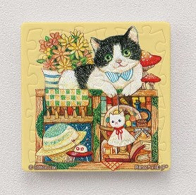 A colorful 16-piece jigsaw puzzle magnet featuring a charming tuxedo cat wearing a bow tie, surrounded by flowers, hats, and whimsical decor. The puzzle showcases vibrant colors and intricate designs, perfect for cat lovers and puzzle enthusiasts.