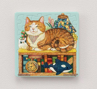 A vibrant and colorful 16-piece jigsaw puzzle magnet featuring a ginger cat lounging on a wooden shelf surrounded by books, a clock, and decorative items. The cat appears content and cozy, with a charming expression and a checkered scarf. This puzzle is made by Cotton Lion and designed by Pintoo, perfect for cat lovers and puzzle enthusiasts.