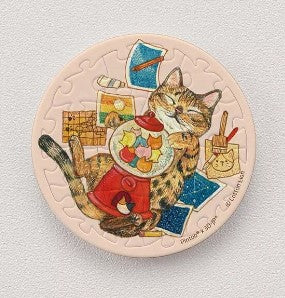 A circular jigsaw puzzle magnet featuring a playful tabby cat surrounded by colorful craft items. The cat is joyfully playing with a jar of colorful shapes, set against a pastel background with intricate details highlighting its fur and the various craft materials around it. This 16-piece puzzle magnet is perfect for cat lovers and puzzle enthusiasts alike.