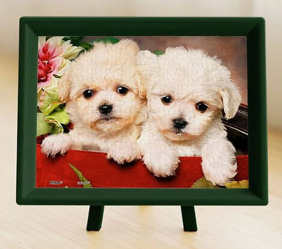 Close-up of an adorable jigsaw puzzle featuring two fluffy puppies nestled in a gift box, surrounded by vibrant flowers. The puzzle is displayed in a stylish green frame, highlighting its charming design and intricate details, ideal for animal lovers and puzzle enthusiasts.