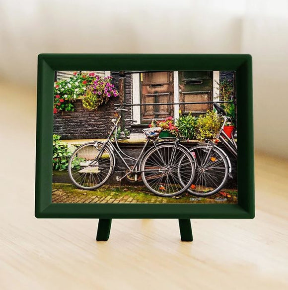 A beautifully framed jigsaw puzzle featuring a picturesque scene of bicycles parked on a charming street in Amsterdam, adorned with colorful flowers and a rustic doorway. The 150-piece puzzle is perfect for cycling enthusiasts and puzzle lovers alike, showcasing the vibrant culture of the Netherlands.