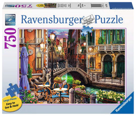 Ravensburger Venice Twilight 750-piece jigsaw puzzle featuring a picturesque canal scene in Venice, with colorful buildings, a charming bridge, and outdoor cafe tables adorned with vibrant flowers. The packaging highlights large, easy-to-handle pieces and claims premium quality with Softclick technology.