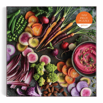 The Garden Board jigsaw puzzle by Galison featuring a colorful arrangement of fresh vegetables and herbs, including carrots, radishes, broccoli, and various sliced root vegetables, set against a dark background. The puzzle consists of 500 pieces, designed for both adults and children to enjoy.