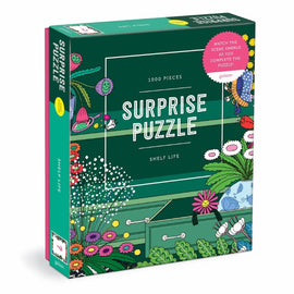 A colorful jigsaw puzzle box titled 'Shelf Life Surprise Puzzle' by Galison, featuring a vibrant design with flowers and gardening themes. The box contains 1000 pieces and has a sticker that says 'Watch the scene emerge as you complete the puzzle!'