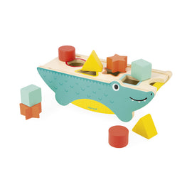 The Tropik Shape Sorting Crocodile features a colorful wooden crocodile with various shaped holes on its back. Included are brightly colored geometric blocks in different shapes and sizes, perfect for young children to practice shape sorting. The crocodile is smiling, adding a playful touch to this engaging learning toy, designed to promote spatial awareness and motor skills.