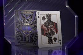 Black Panther playing cards by Theory 11, featuring an ornate deck box with a purple and black design. The King of Spades card displayed shows a stylized Black Panther character with crossed arms and intricate patterns.