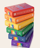 A colorful stack of DKNG Rainbow Wheels Playing Cards by Art of Play. The boxes are displayed in vibrant rainbow colors including red, orange, yellow, green, blue, and purple. Each box is designed with intricate patterns and labeled with 'Premium Quality Playing Cards' and 'Poker' alongside the year '1984.' Perfect for card games and collectors.