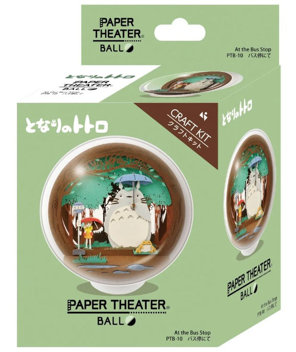 Paper Theater Ball featuring Totoro at the Bus Stop. This DIY craft kit by Ensky includes intricate paper designs depicting Totoro and a young girl under an umbrella surrounded by trees. The product is packaged in a colorful box, highlighting the creative diorama experience.