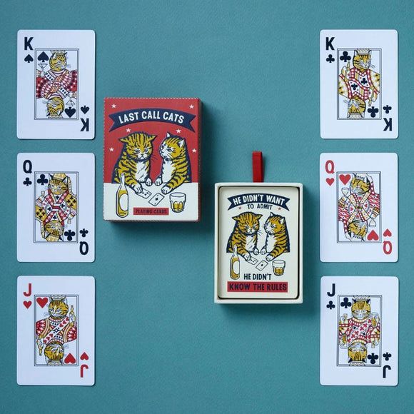 The Last Call Cats Playing Cards from Chronicle Books, featuring a colorful box with two illustrated cats enjoying drinks and surrounded by playing cards on a teal background. Cards include King, Queen, and Jack, each adorned with cat illustrations, adding a whimsical touch to your card games.