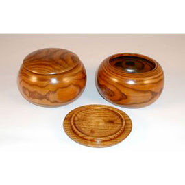 A set of two wooden bowls with a smooth, polished finish. The bowls have rounded shapes and are accompanied by a matching round lid. Perfect for storage or as decorative pieces.