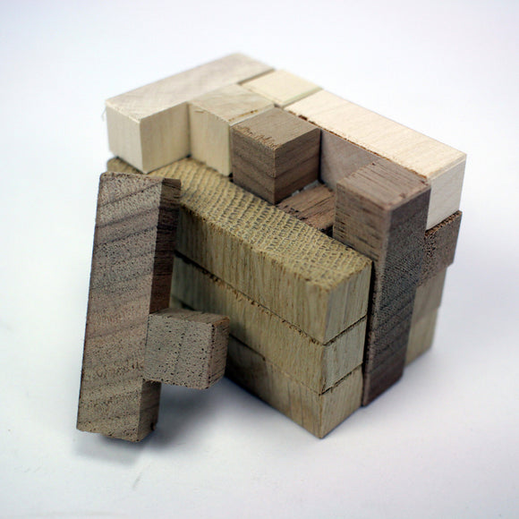 The Minos T by Bernhard Schweitzer is a wooden mechanical puzzle featuring various shaped blocks assembled in a compact design. The puzzle showcases different wood tones and textures, with one block slightly protruding, hinting at the challenge of disassembling or reassembling it. Ideal for puzzle enthusiasts looking to test their problem-solving skills.