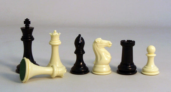A collection of 4-inch triple-weighted chess pieces displayed. The set includes a black king, black queen, white king, black bishop, white knight, black rook, and a white pawn, showcasing a mix of black and white pieces that are elegantly designed for a classic chess game.