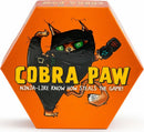 Cobra Paw game by Bananagrams featuring a cartoon cat dressed as a ninja. The box is hexagonal and vibrant orange, showcasing the title 'Cobra Paw' in bold letters, along with the tagline 'Ninja-like know how steals the game!' The playful design appeals to both children and adults seeking a fun, fast-paced game.