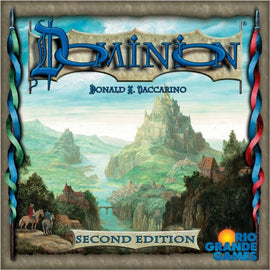 Dominion (Second Edition) board game by Rio Grande Games features an elaborate cover art depicting a fantasy landscape with hills, a castle, and a river. The title 'Dominion' is prominently displayed in blue at the top, with the designer's name, Donald X. Vaccarino, beneath it, and 'Second Edition' at the bottom.