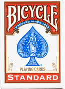 A package of Bicycle Standard playing cards featuring a bold red and white design with a blue spade symbol at the center, adorned with an intricate illustration of a lady in the spade with stars around it, emphasizing the trusted quality of the cards since 1885.