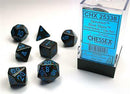 A Speckled Blue Stars Polyhedral Dice Set by Chessex featuring seven glossy dice in various shapes including a D20, D12, D10, D8, D6, and D4. The dice are primarily dark blue with a sparkly star pattern and bright blue numbering. The set is displayed in a clear plastic box with a label on the front.